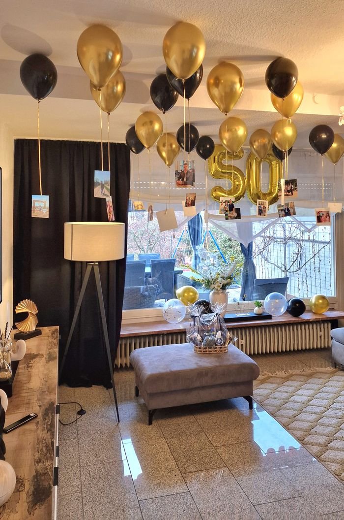 Stylish living room decorated with gold and black balloons for a 50th birthday celebration.